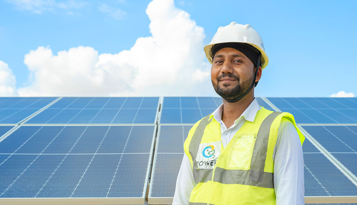 Worker in front of solar panels looking toward the future